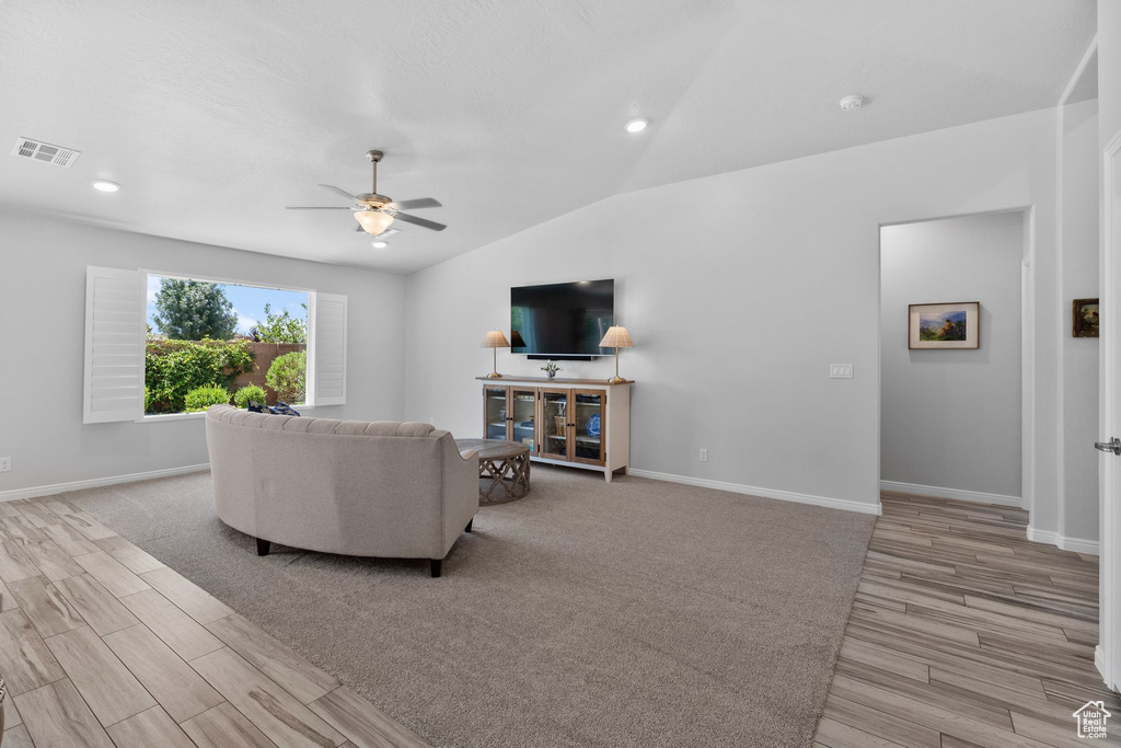 Living area with light wood finished floors, ceiling fan, lofted ceiling, and recessed lighting