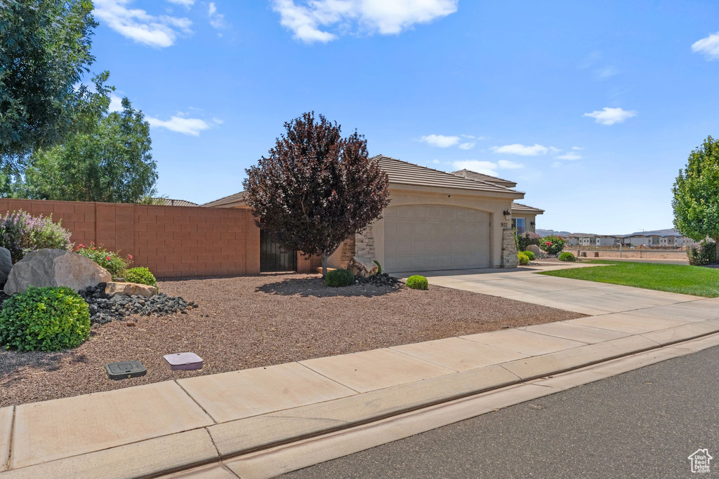 View of front facade with an attached garage, driveway, a tile roof, and stucco siding