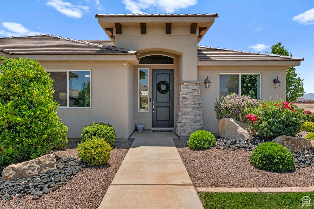 View of front of home featuring stucco siding, a tiled roof, and stone siding