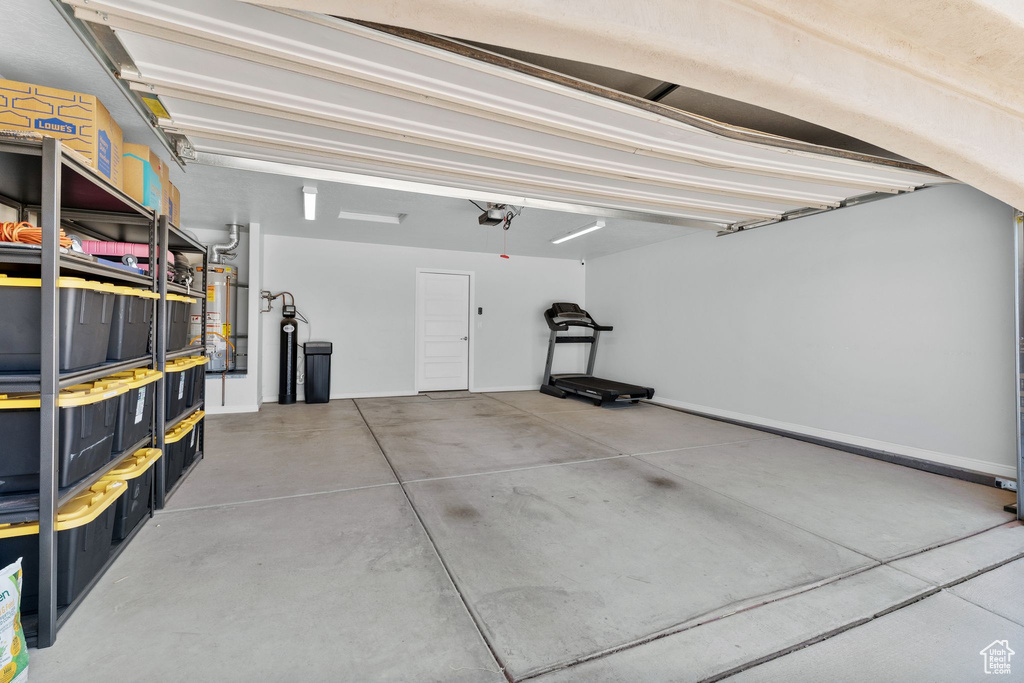Garage featuring strapped water heater and a garage door opener