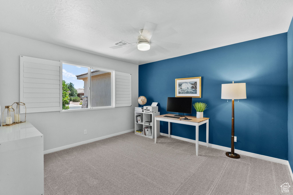 Carpeted home office with a ceiling fan and baseboards