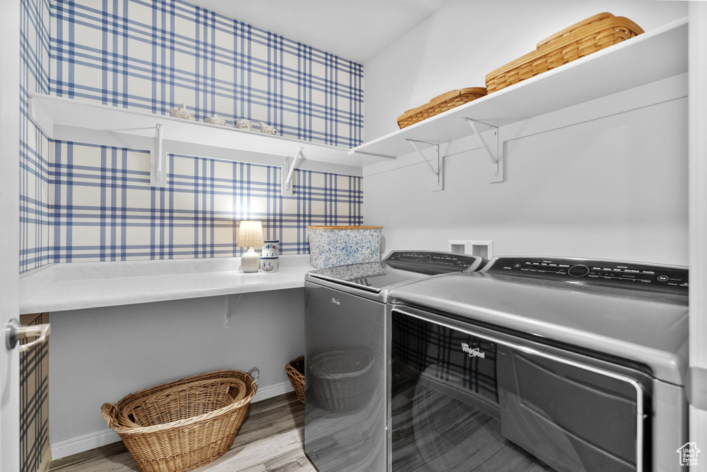 Laundry room with washing machine and clothes dryer and light wood-style floors