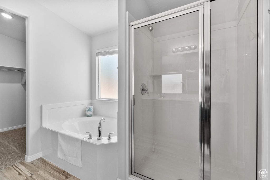 Full bathroom featuring a stall shower, a bath, wood finished floors, and a walk in closet