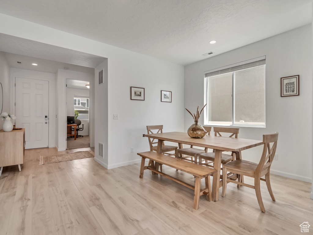 Dining area with light wood-style floors and recessed lighting
