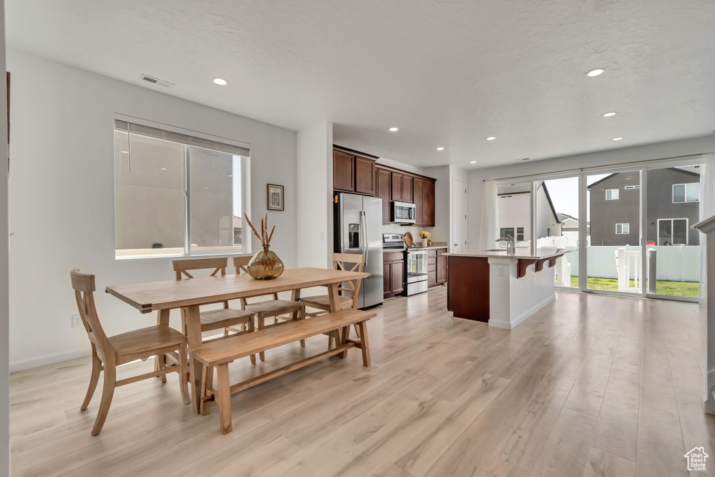 Dining space with light wood-style floors and recessed lighting