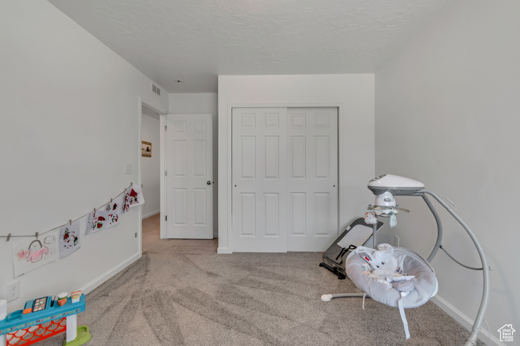 Recreation room featuring carpet flooring and a textured ceiling