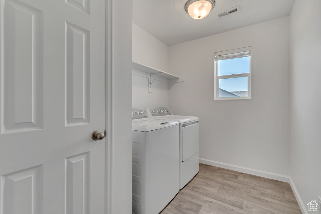 Laundry room with independent washer and dryer and light wood-style floors