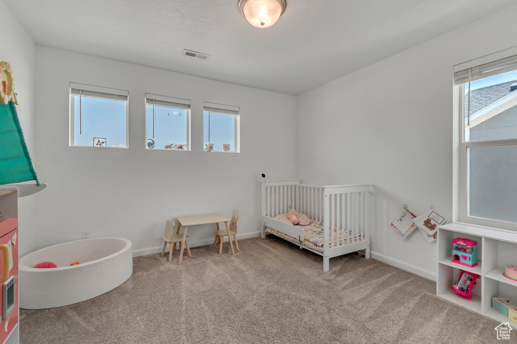 Carpeted bedroom with a nursery area and baseboards