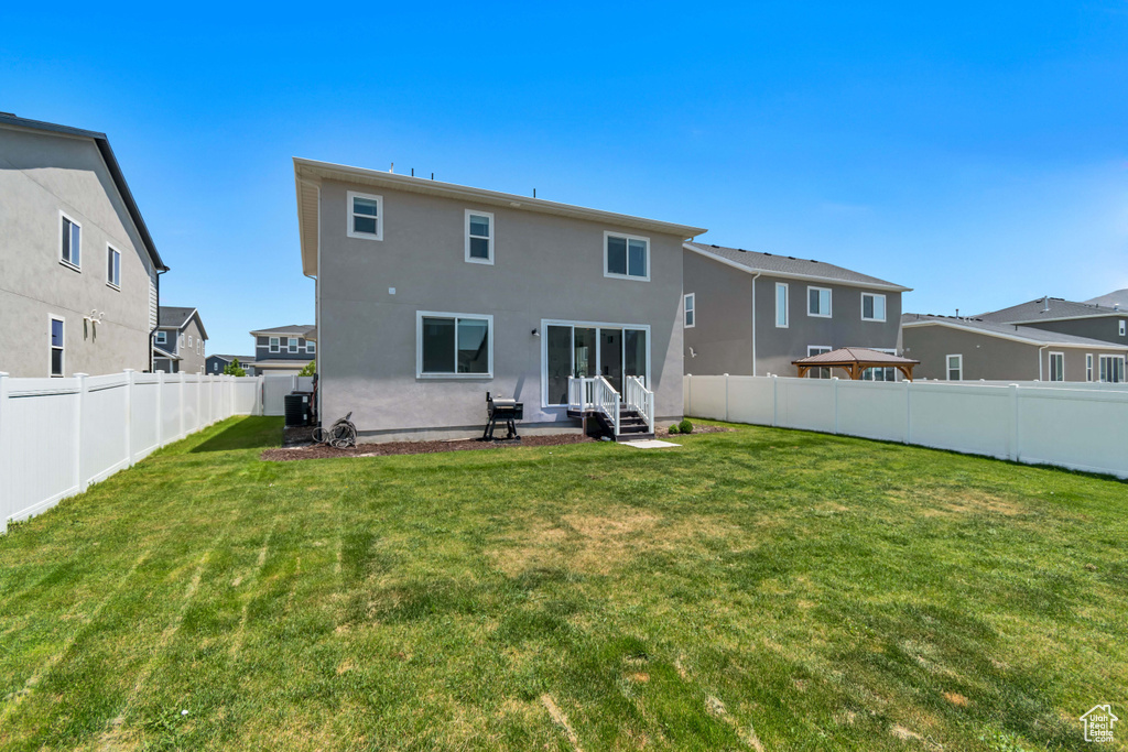 Back of house featuring entry steps, a fenced backyard, stucco siding, and a residential view