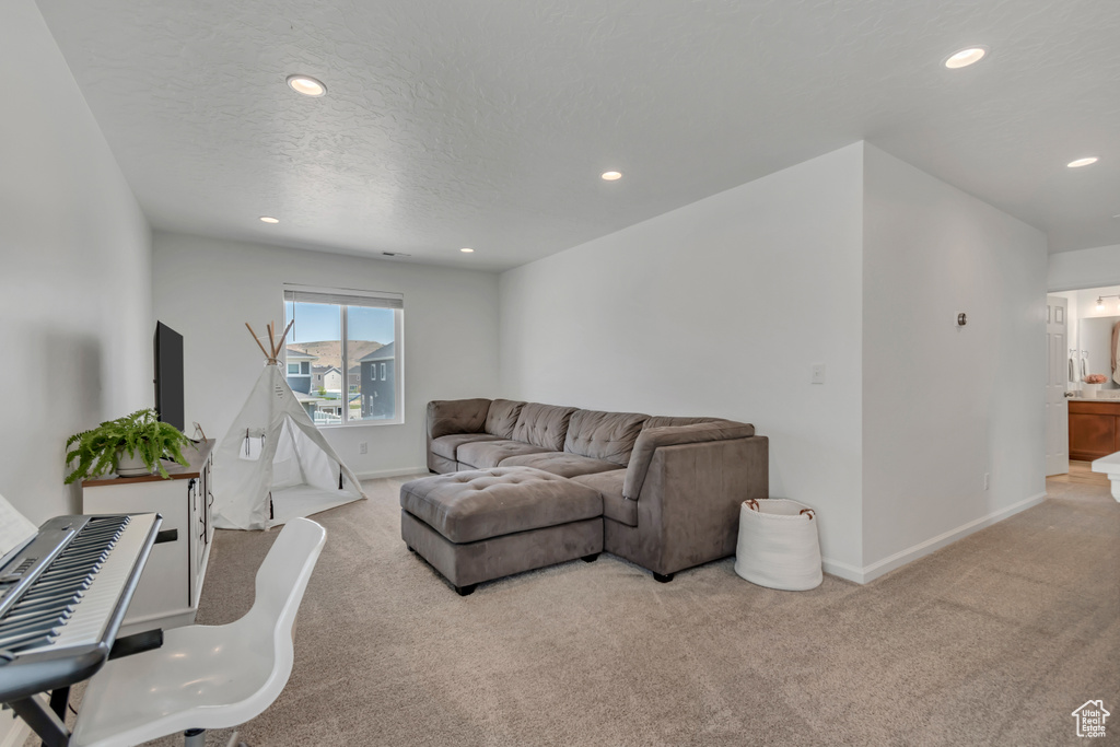 Carpeted living area with recessed lighting and a textured ceiling