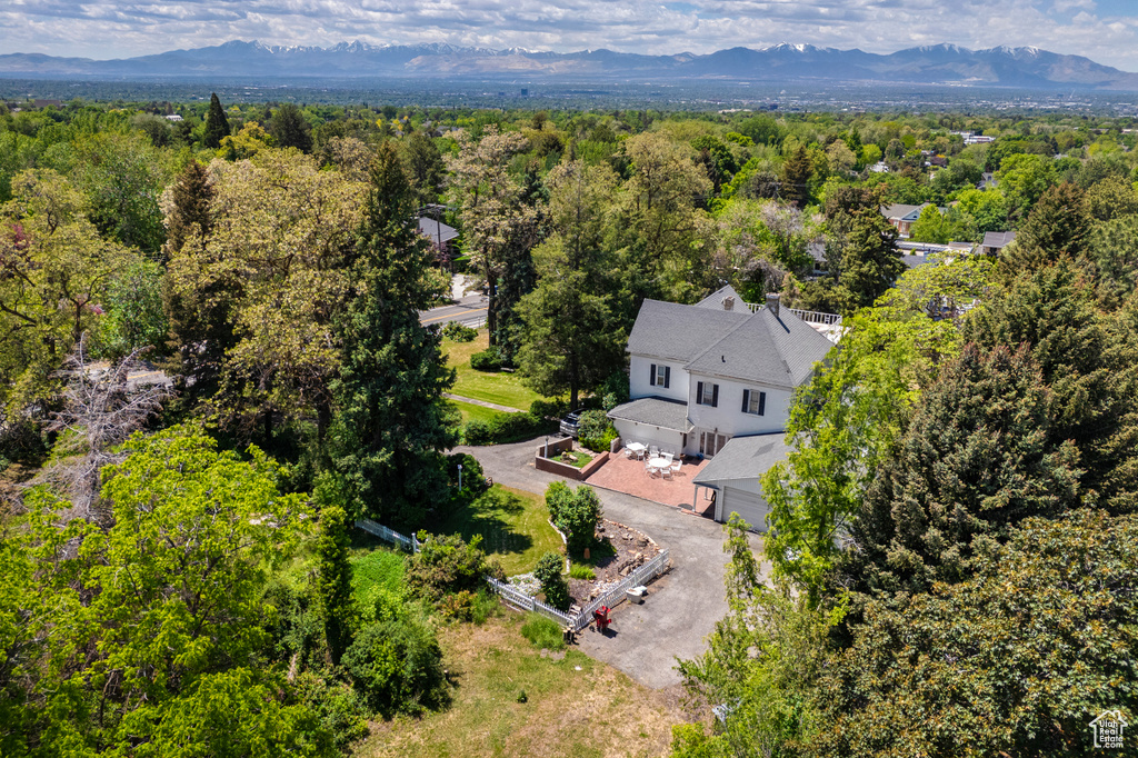 Aerial view of property and surrounding area with a mountainous background and a heavily wooded area