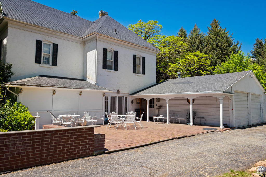 Back of property featuring a shingled roof, outdoor dining area, a patio area, and a chimney