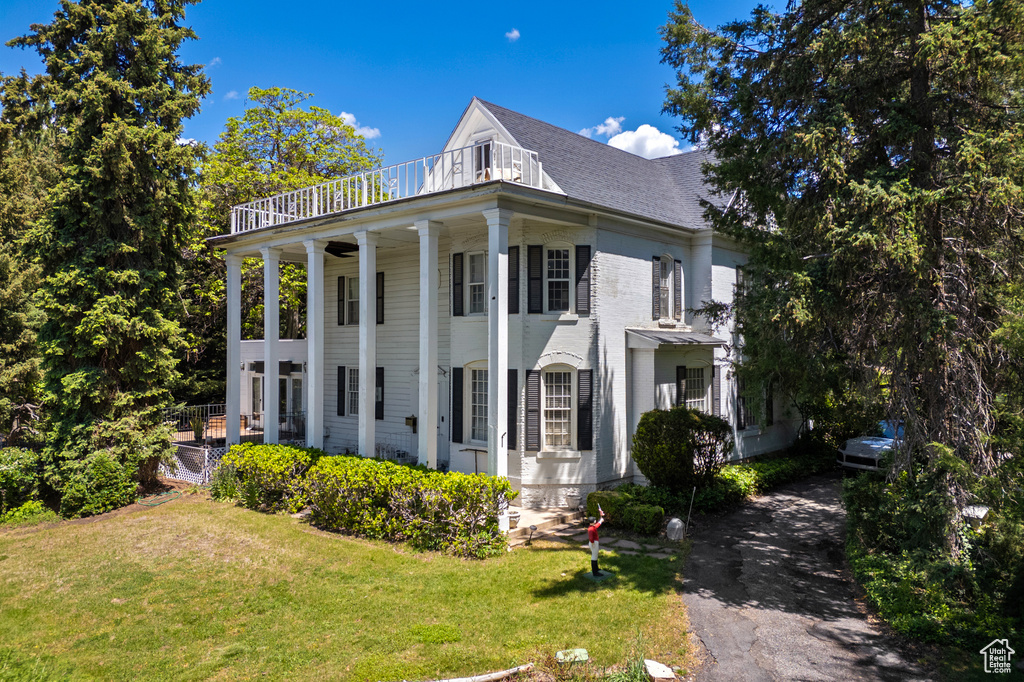 View of home\'s exterior featuring a lawn, a balcony, asphalt driveway, and roof with shingles