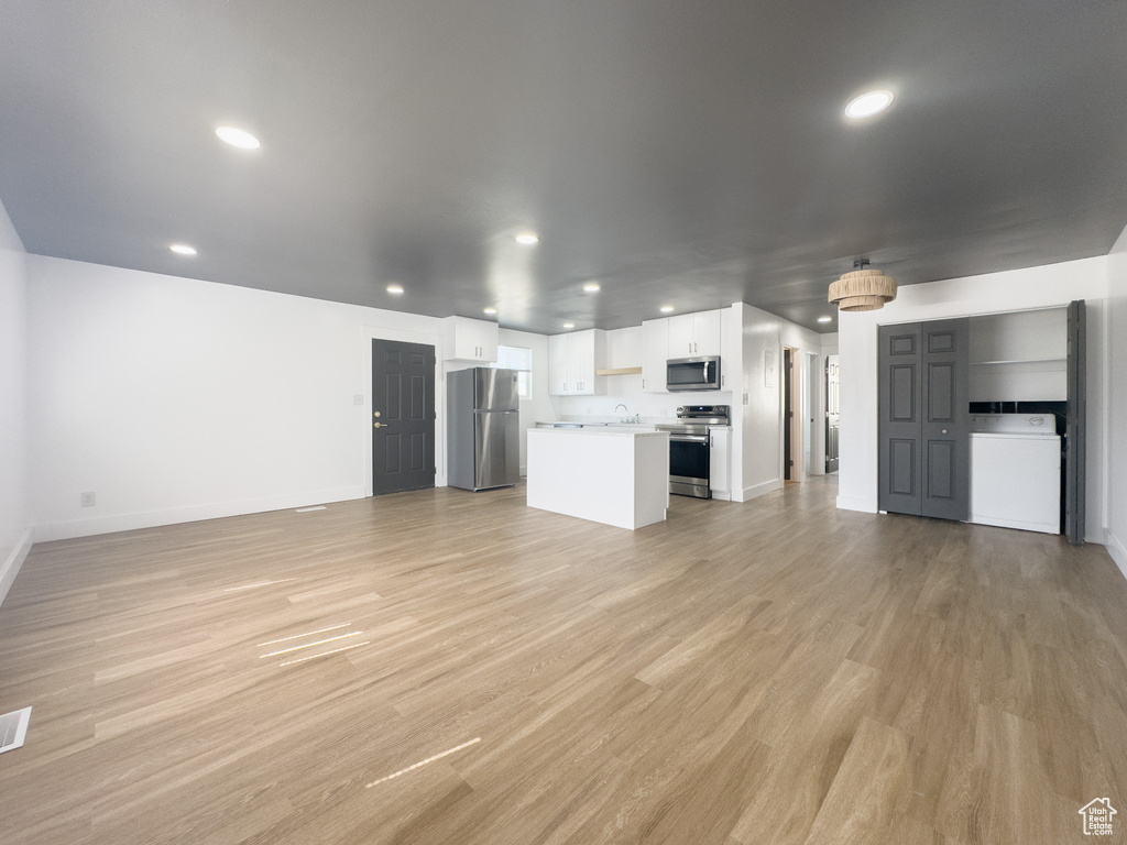Unfurnished living room with washer / dryer, light wood finished floors, and recessed lighting