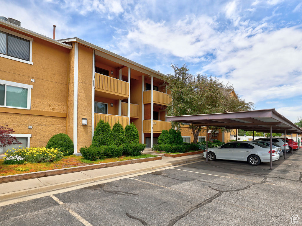 View of building exterior featuring covered and uncovered parking