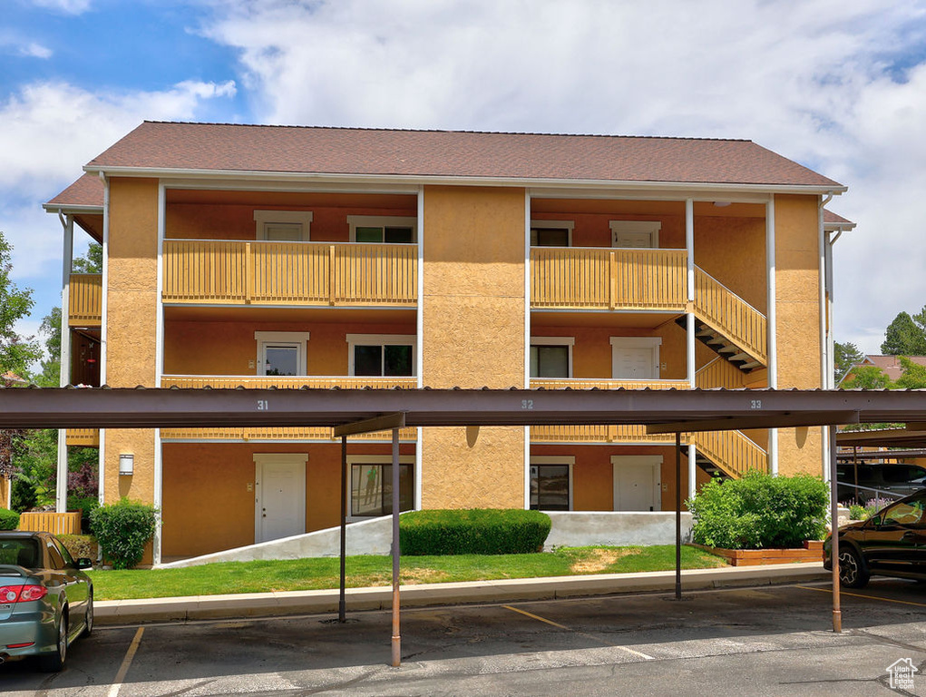View of apartment building / complex featuring stairway and covered parking