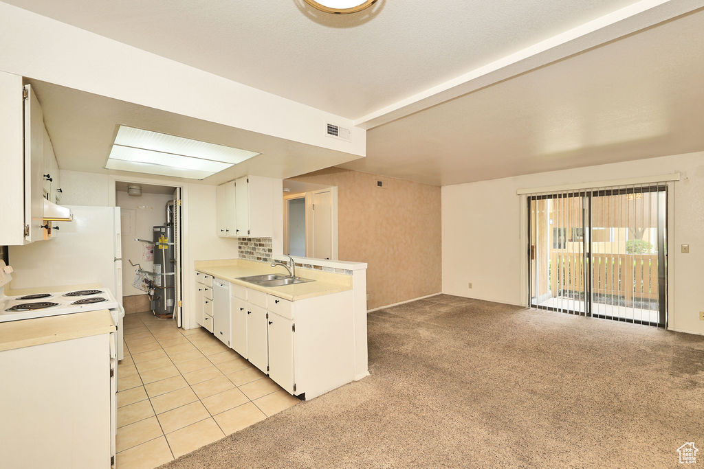 Kitchen with light countertops, a peninsula, white cabinets, and strapped water heater