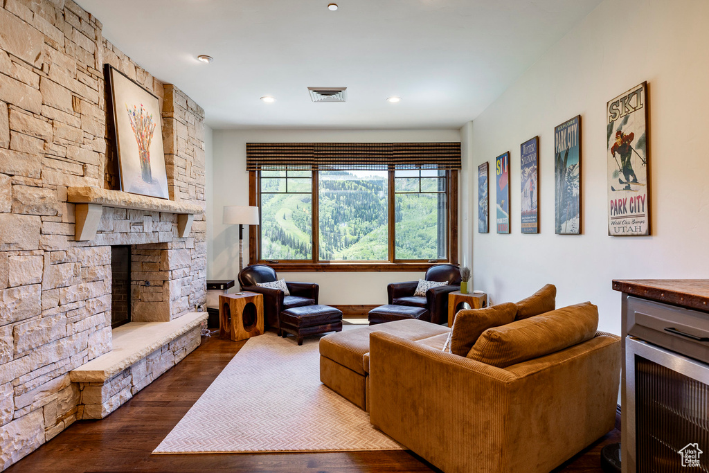 Living room with a fireplace, dark wood-style floors, and recessed lighting