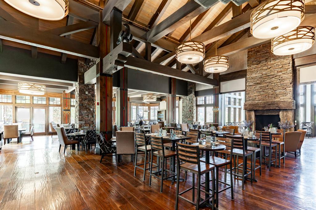Dining space featuring high vaulted ceiling, hardwood / wood-style flooring, a wooden ceiling with exposed beams, and a fireplace