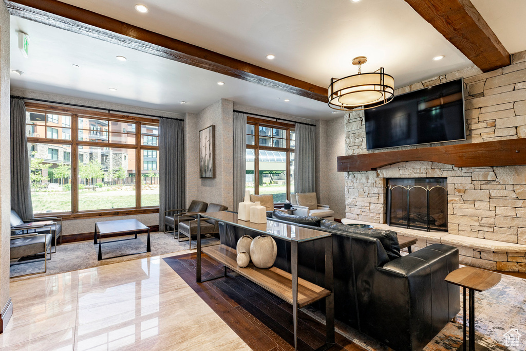 Living area with beamed ceiling, a stone fireplace, and recessed lighting