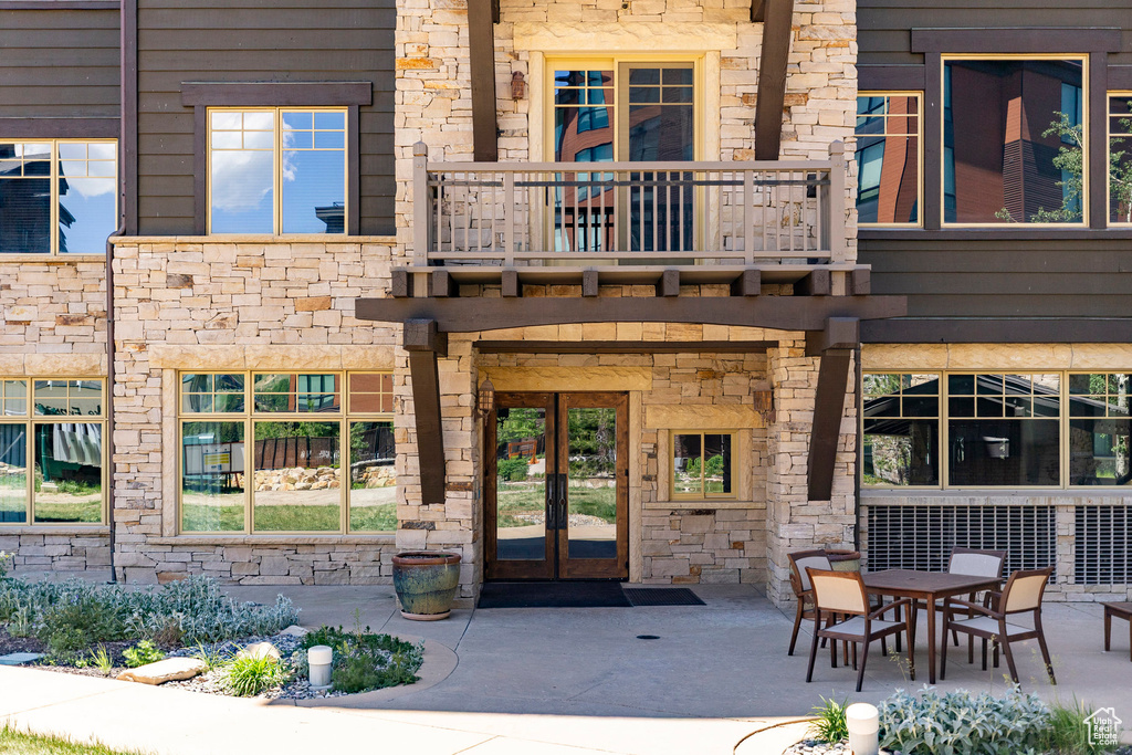 Property entrance with stone siding, french doors, a balcony, and a patio area