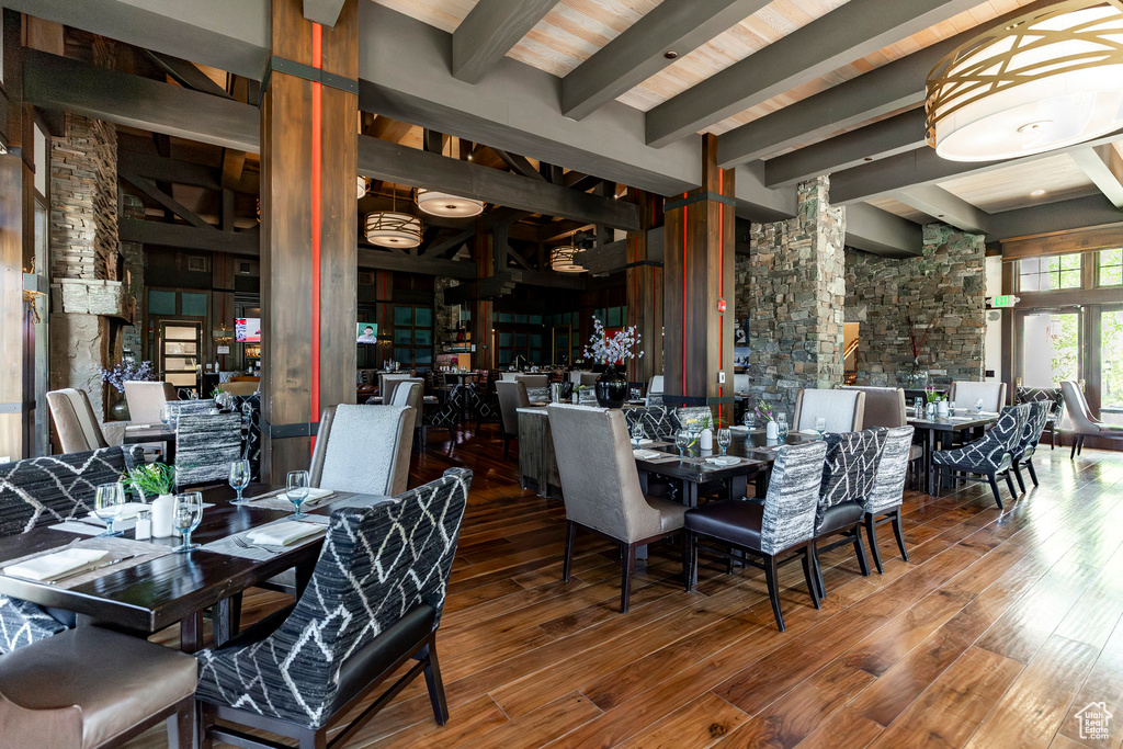 Dining area featuring beam ceiling, decorative columns, and hardwood / wood-style flooring