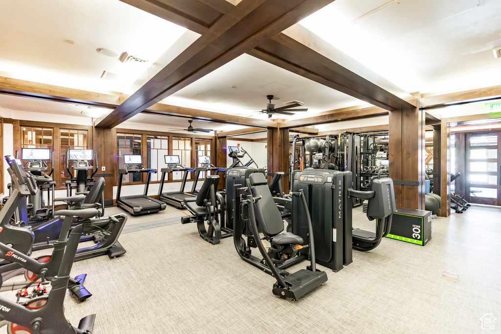 Exercise room featuring ceiling fan, beamed ceiling, and carpet