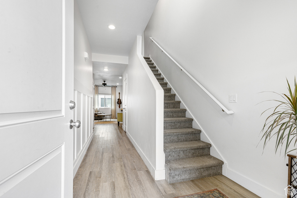 Staircase with wood finished floors and recessed lighting