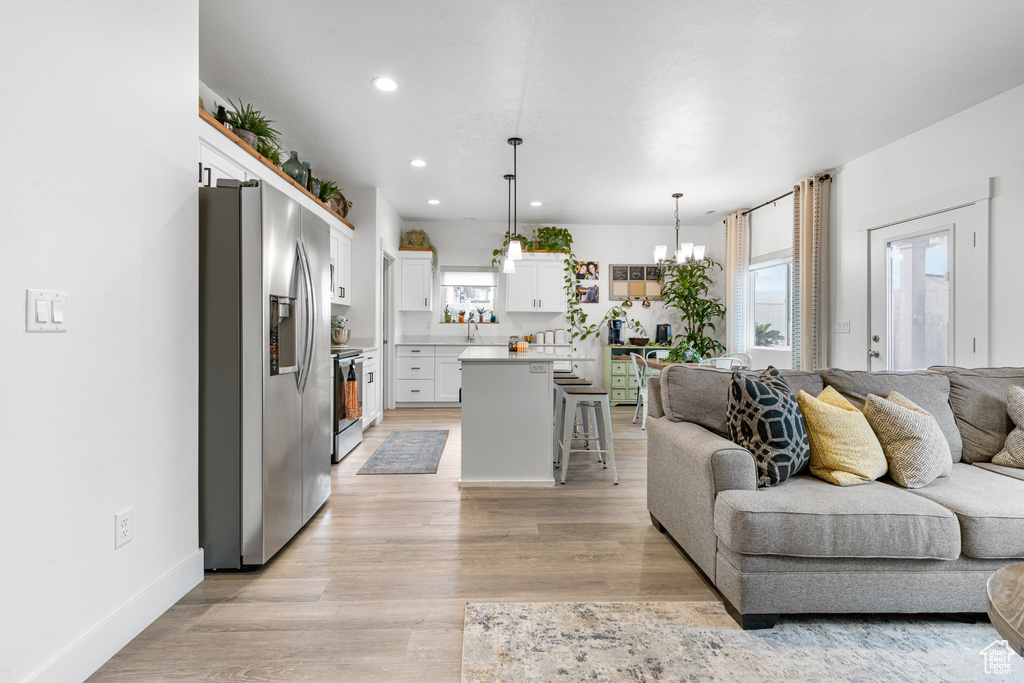 Living room featuring recessed lighting, light wood-type flooring, and a chandelier