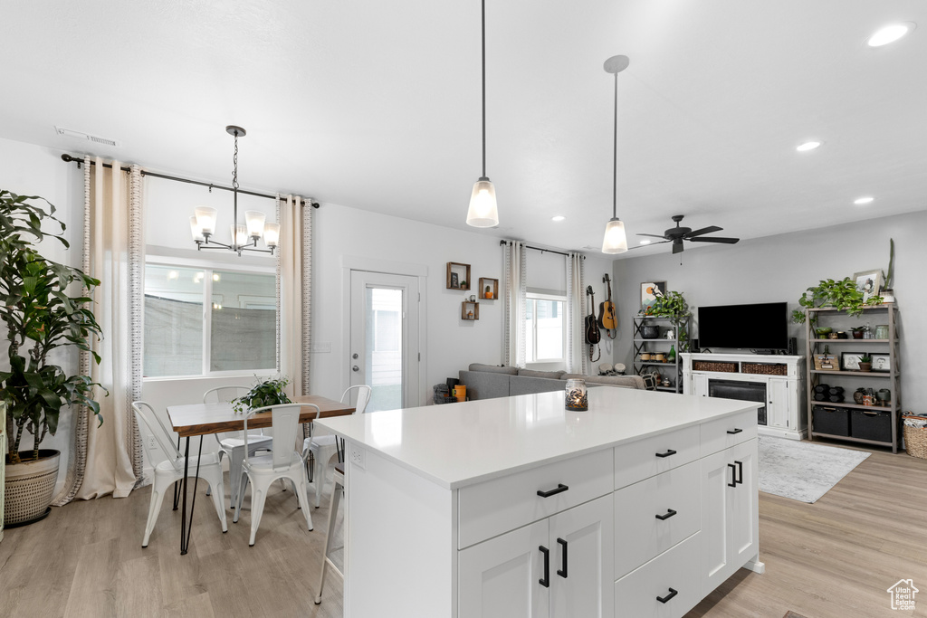 Kitchen featuring light wood finished floors, ceiling fan, recessed lighting, a chandelier, and a kitchen island