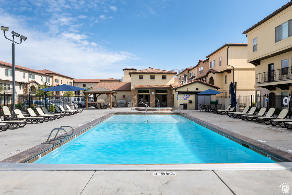Community pool featuring a gazebo, a patio area, and a residential view