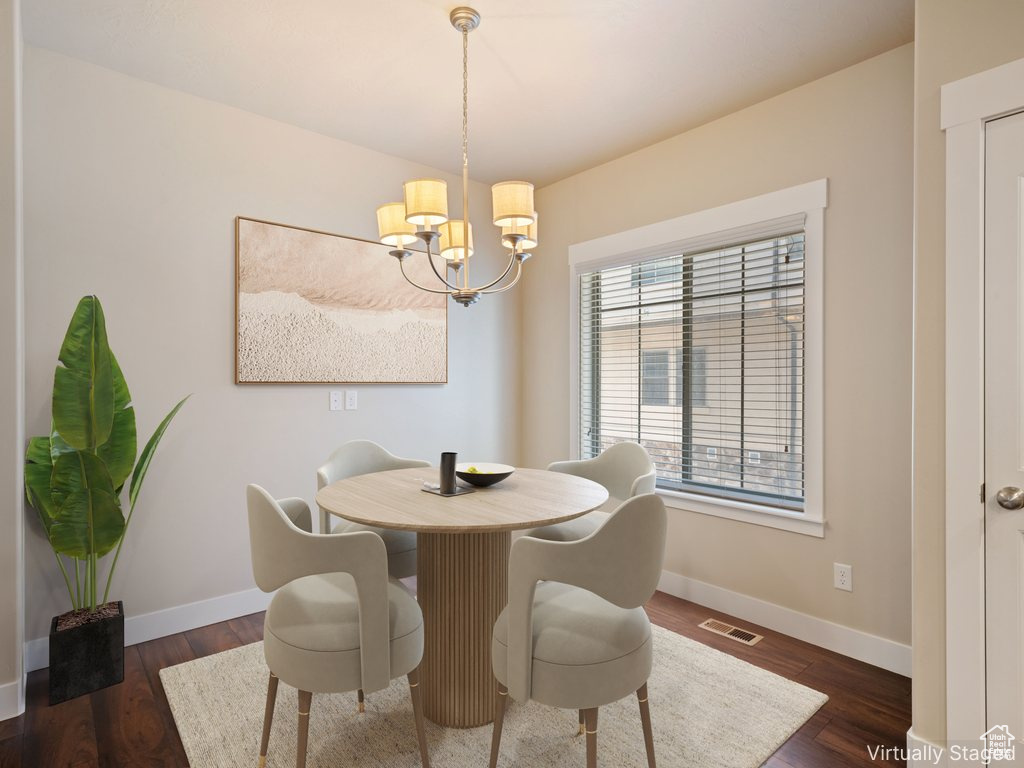Dining space with a chandelier and dark wood-type flooring