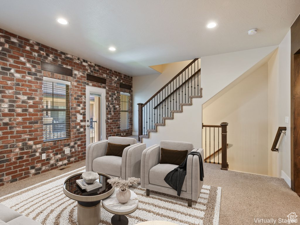 Carpeted living area with recessed lighting, brick wall, and stairway