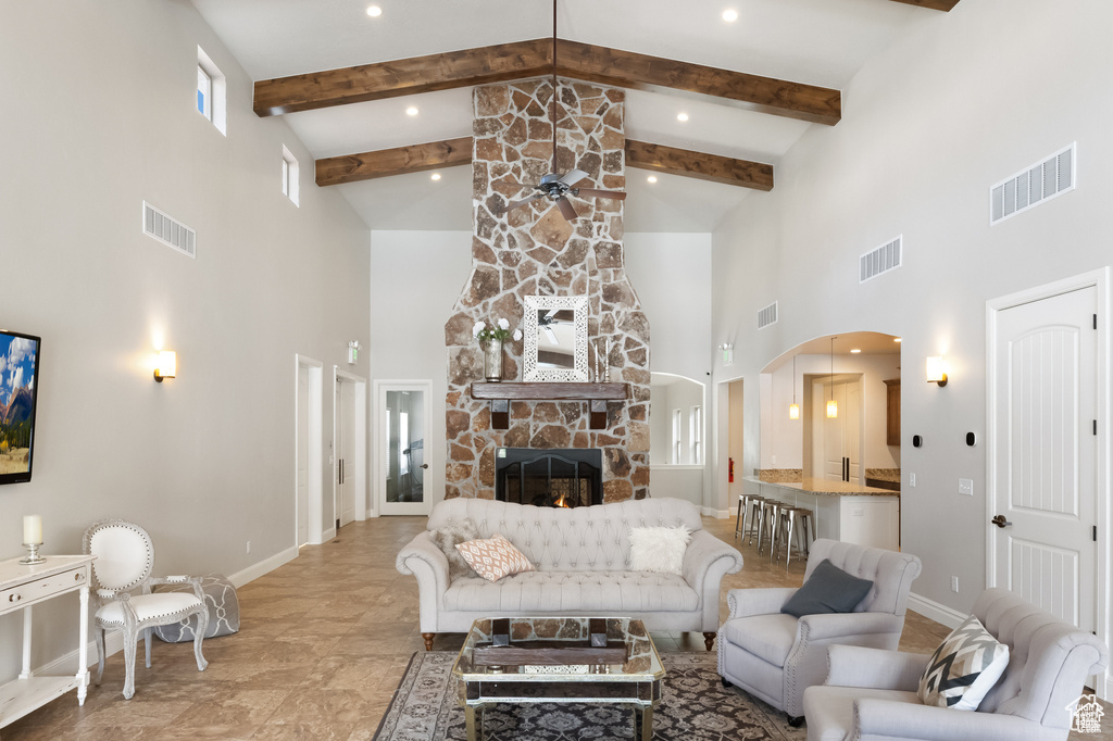 Living area with high vaulted ceiling, arched walkways, beam ceiling, a fireplace, and ceiling fan