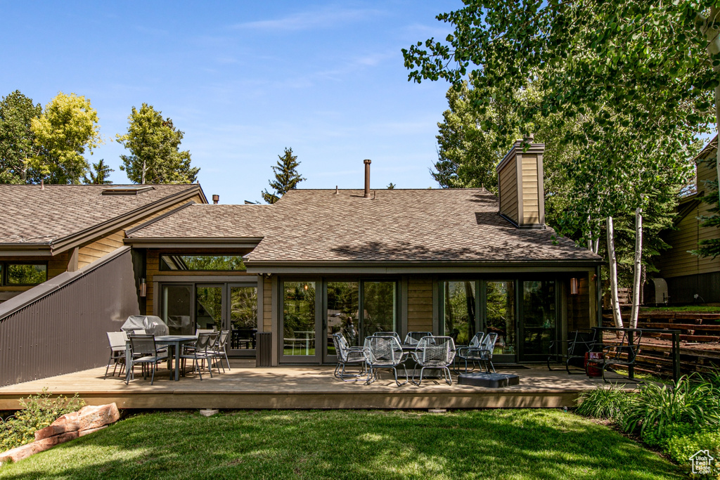 Rear view of property with outdoor dining space, a wooden deck, a chimney, and a shingled roof
