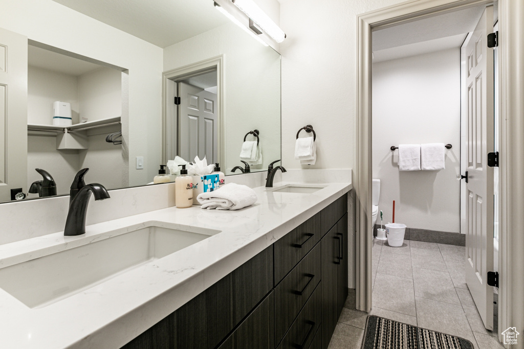 Full bathroom featuring double vanity, tile patterned floors, and a closet