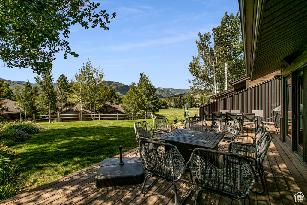 Deck featuring outdoor dining space, a yard, and a mountain view