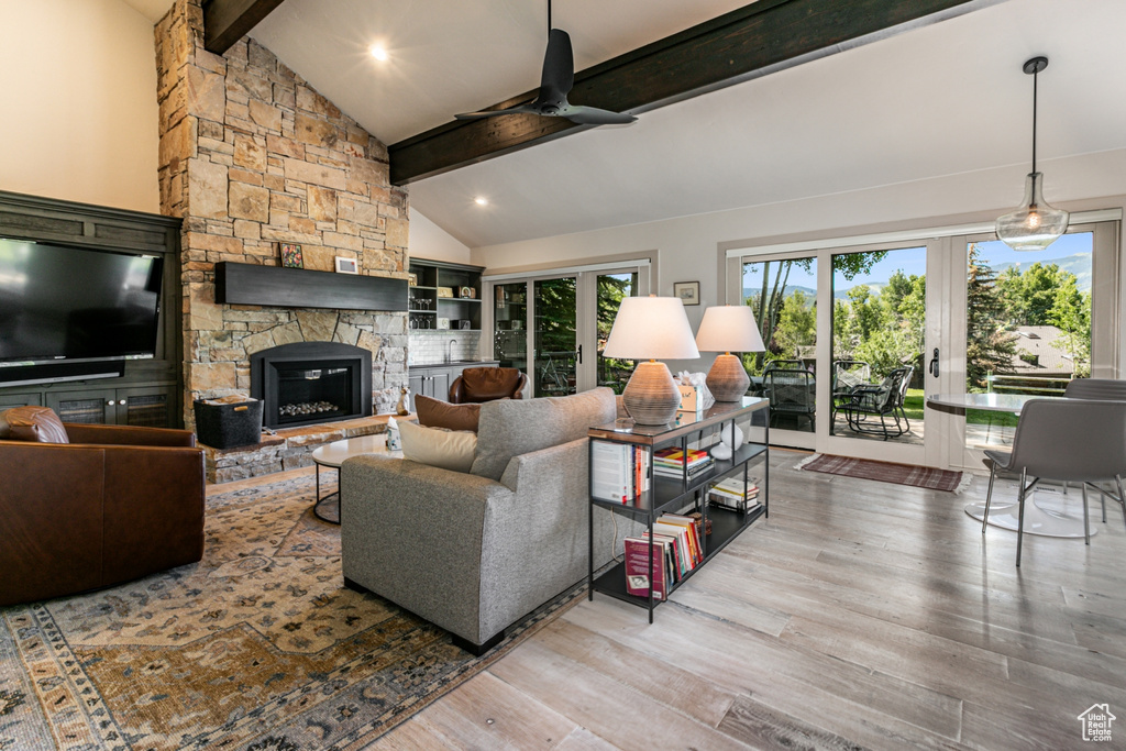 Living room featuring a ceiling fan, a stone fireplace, french doors, and wood finished floors