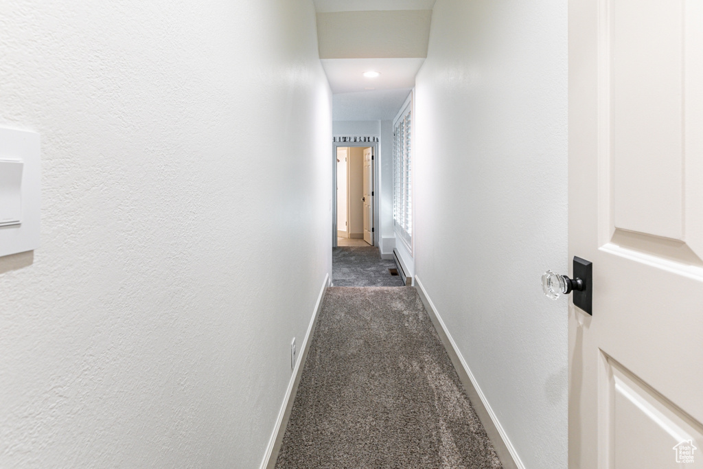 Corridor featuring dark colored carpet and recessed lighting