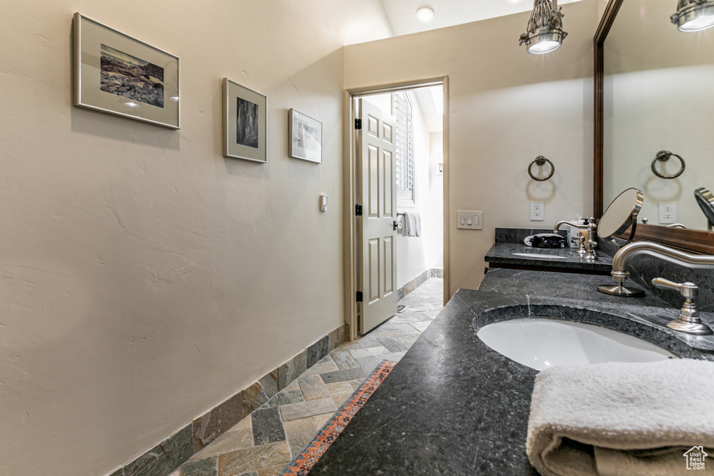 Bathroom featuring inlaid floor details, double vanity, and stone tile flooring
