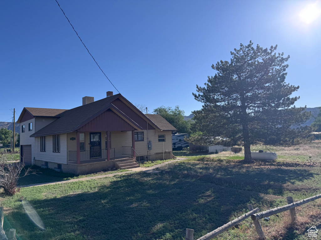 Back of house featuring a porch, a lawn, and a chimney