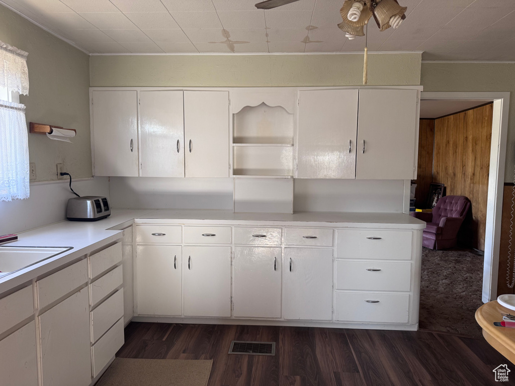 Kitchen featuring light countertops, dark wood-style flooring, white cabinets, ceiling fan, and crown molding