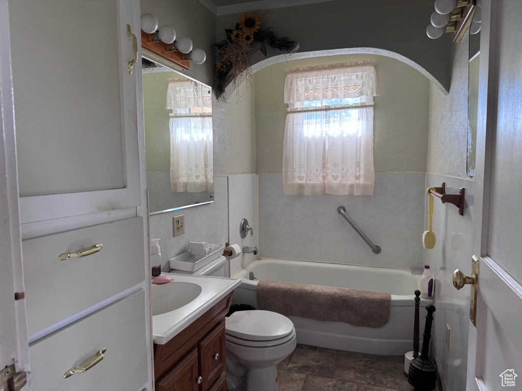 Full bath featuring vanity, a garden tub, and stone finish flooring