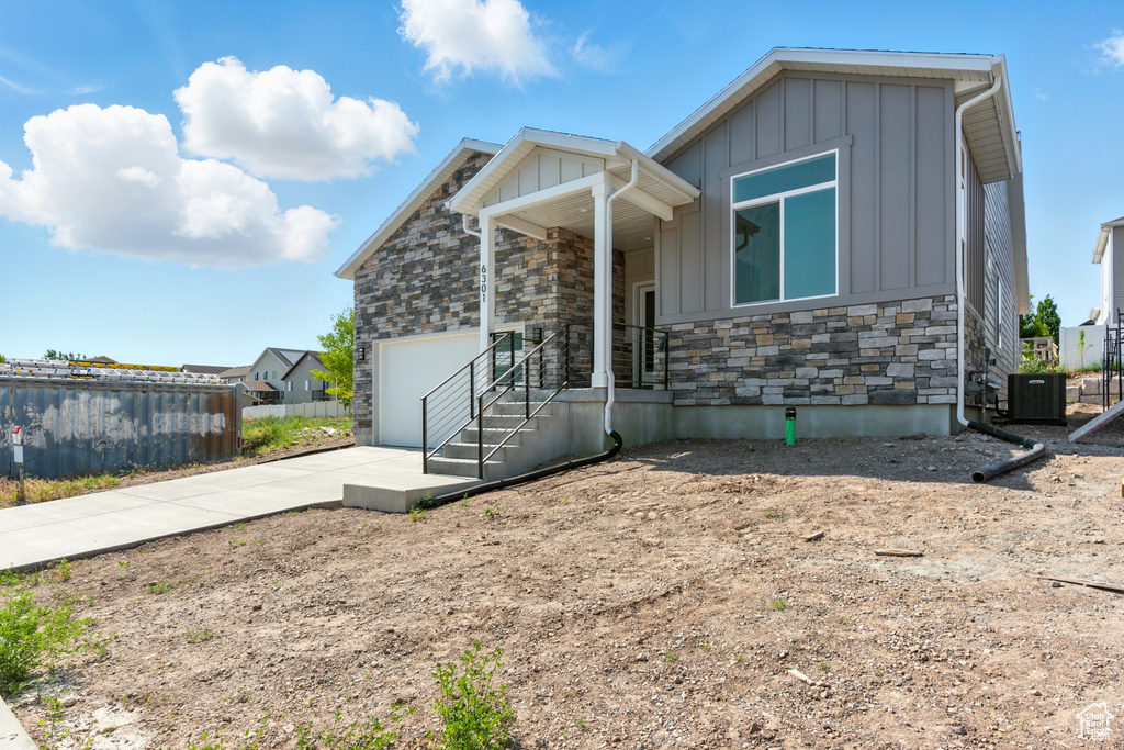 View of front facade featuring stone siding, board and batten siding, concrete driveway, and an attached garage