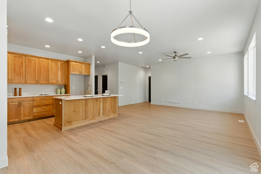 Kitchen featuring recessed lighting, light countertops, a kitchen island with sink, light wood finished floors, and a ceiling fan