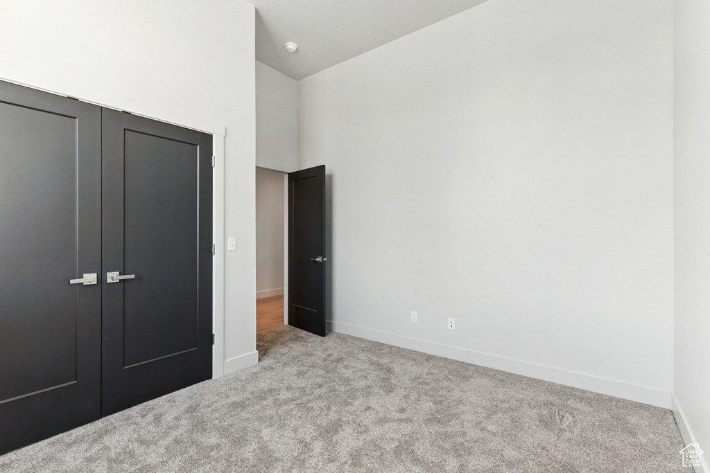 Unfurnished bedroom featuring carpet flooring, a closet, and high vaulted ceiling