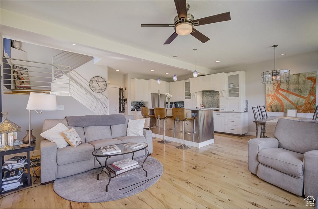 Living area with stairway, ceiling fan, light wood finished floors, and recessed lighting