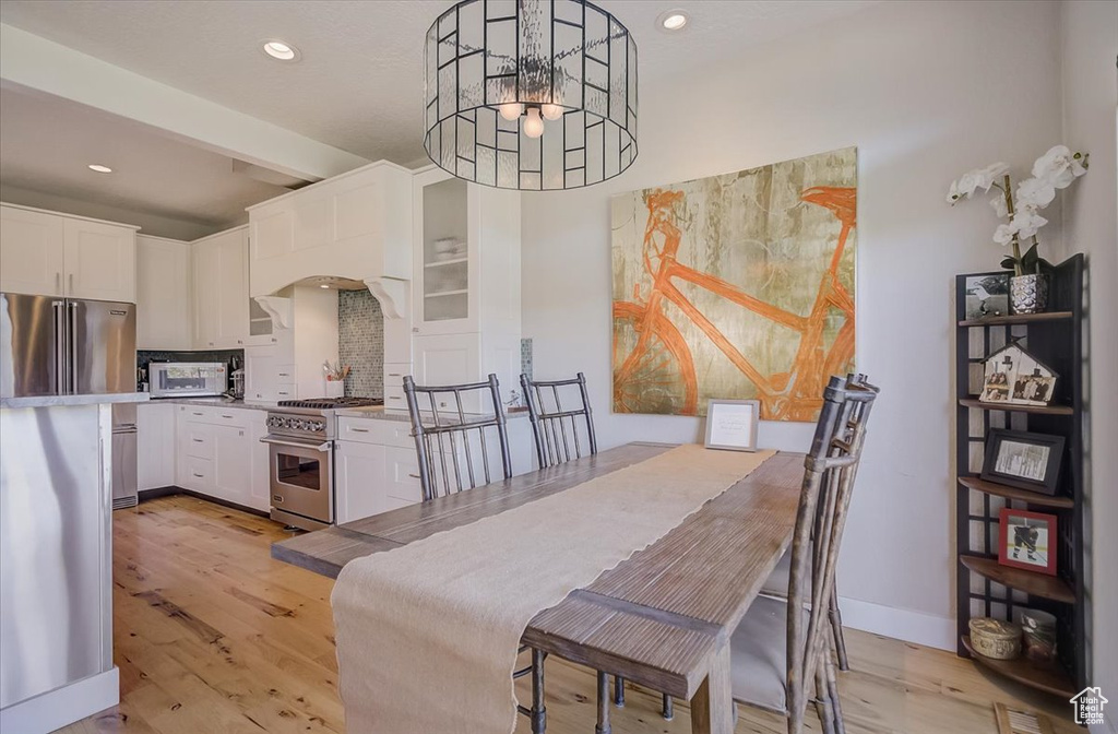Dining space with light wood-style floors, a chandelier, recessed lighting, arched walkways, and beam ceiling