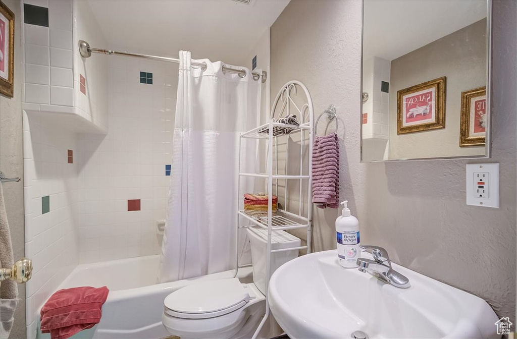 Bathroom with a textured wall and shower / tub combo with curtain