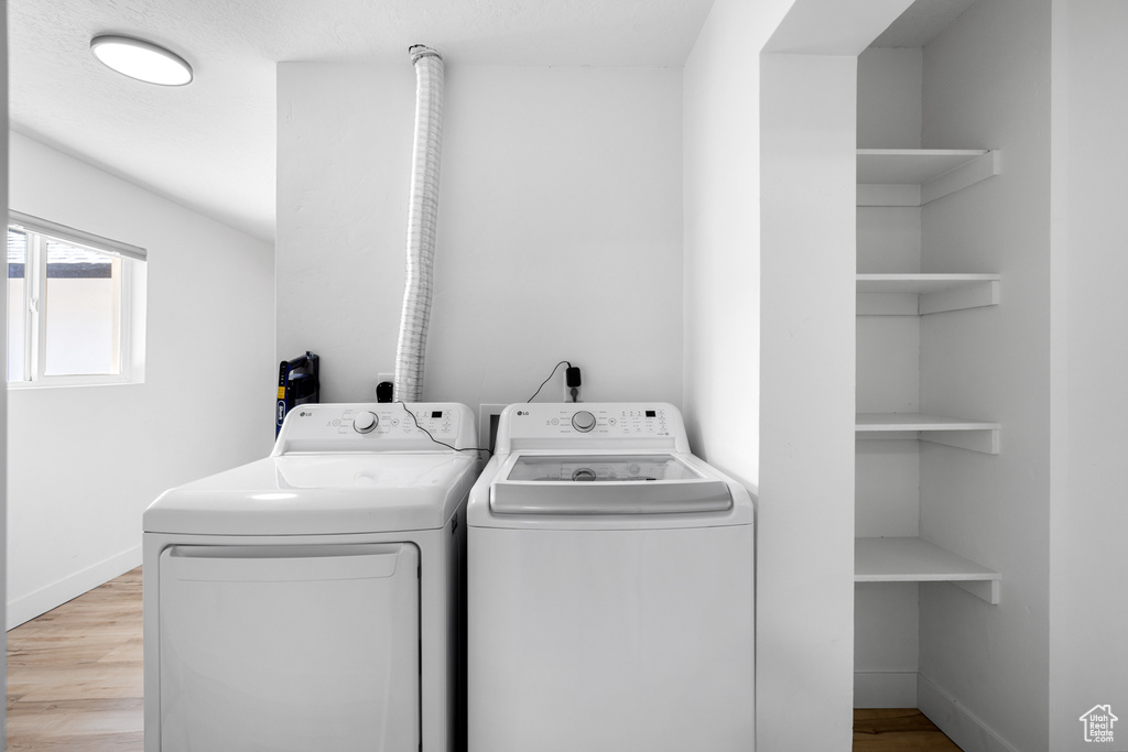 Washroom featuring washer and clothes dryer and light wood finished floors